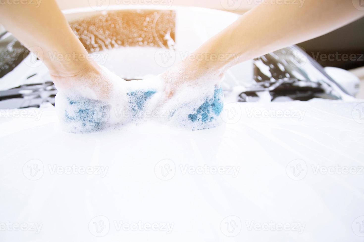 people hand hold blue sponge washing car. photo