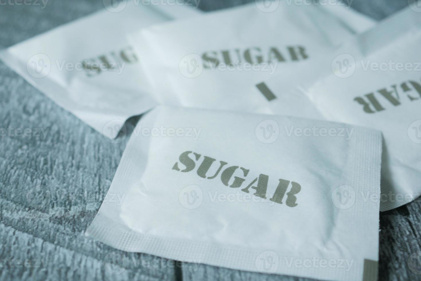 close up of white sugar in a paper packet on table photo