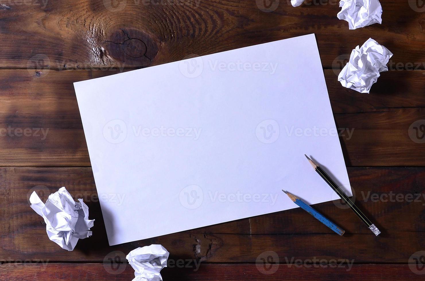 Photo of a clean white blank sheet of paper lie on a brown wooden background. Plenty of space for text