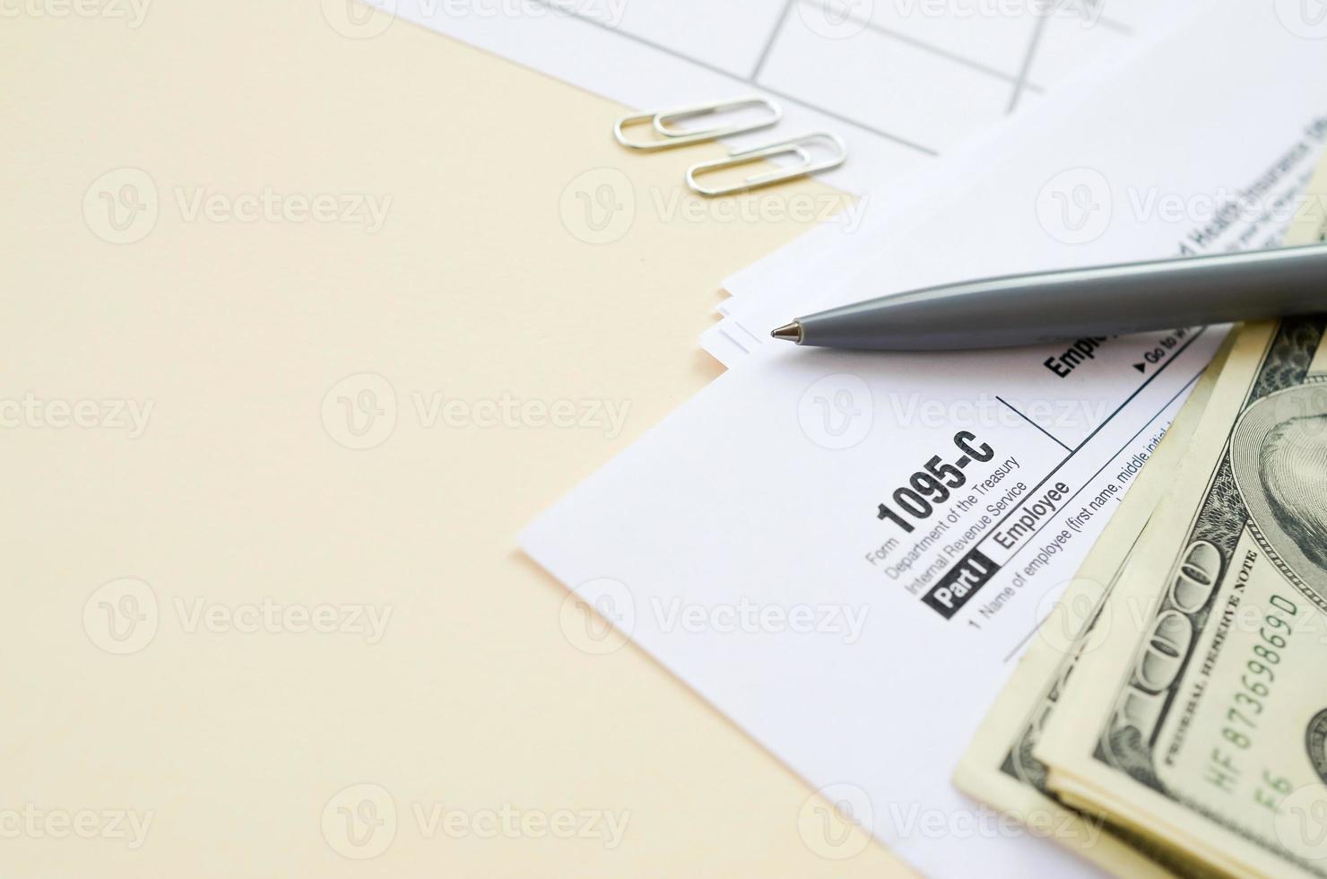 IRS Form 1095-C Employer-Provided Health Insurance Offer and Coverage tax blank lies with pen and many hundred dollar bills on calendar page photo