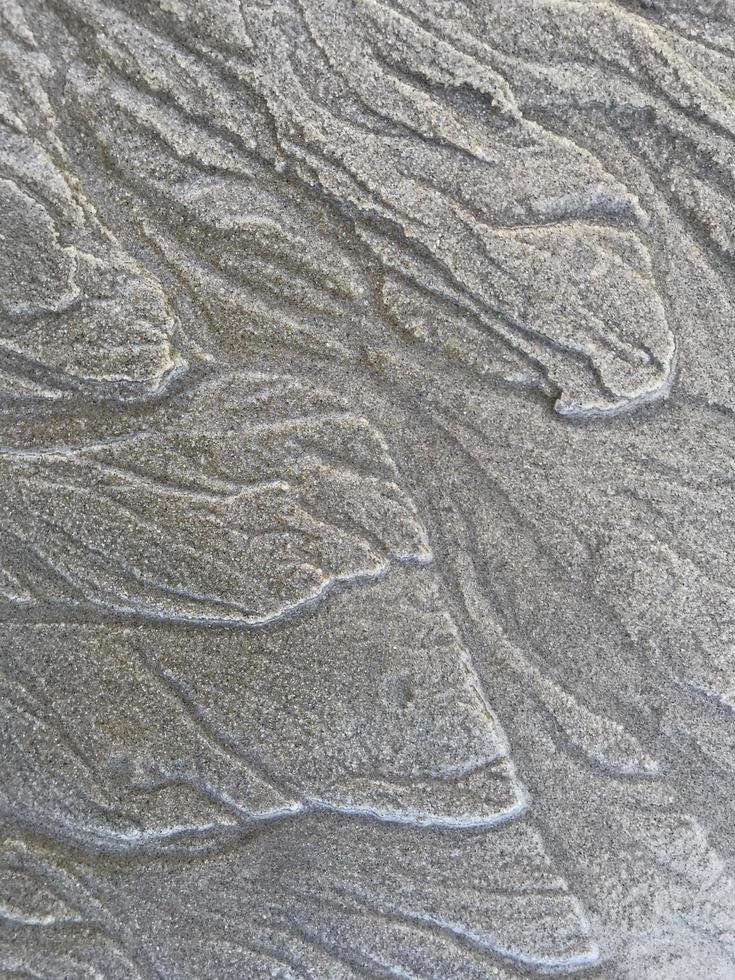 This is a picture of a background of sand on the beach that has just been washed away by the waves photo