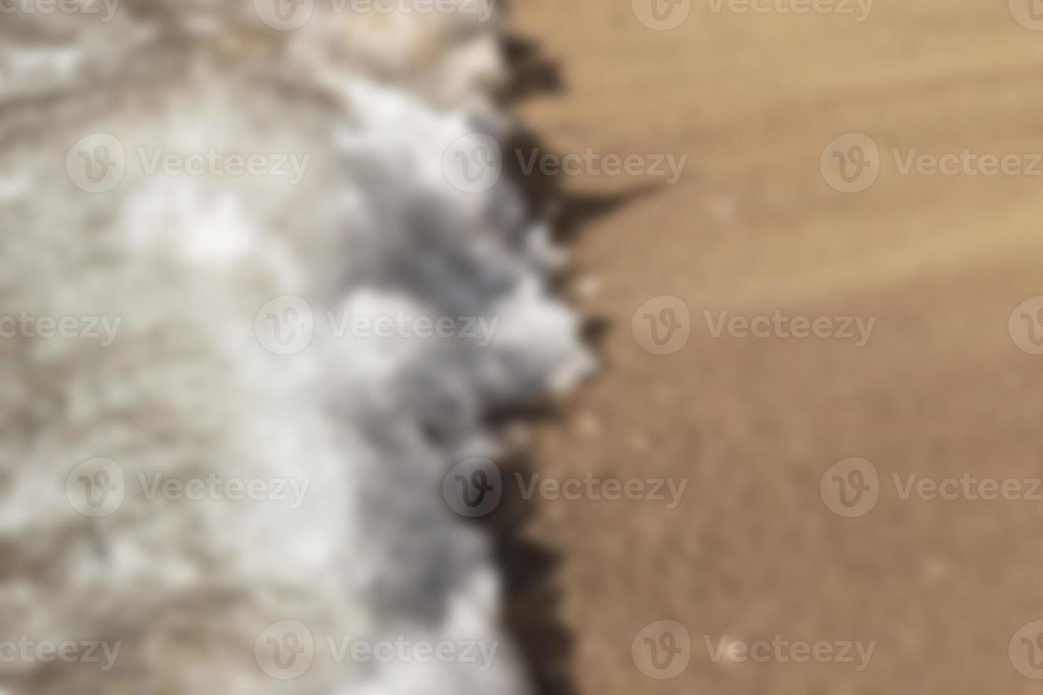 Blurred background, breaking wave on the sandy shore, top view. Background. photo