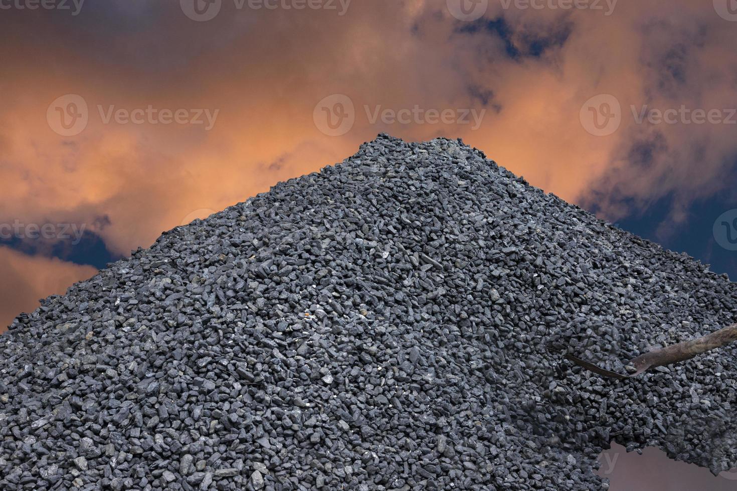 A pile of coal, a mountain of coal with a full shovel of coal against the backdrop of the sunset. Energy crisis. photo