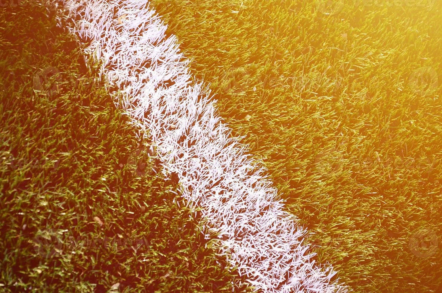 White stripe on a bright green artificial grass soccer field photo