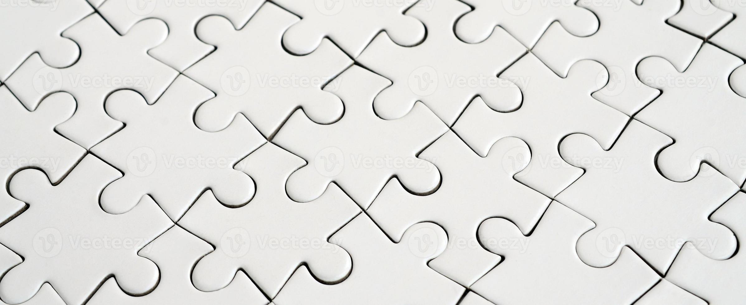 Close up of a white jigsaw puzzle in assembled state in perspective. Many components of a large whole mosaic are united photo