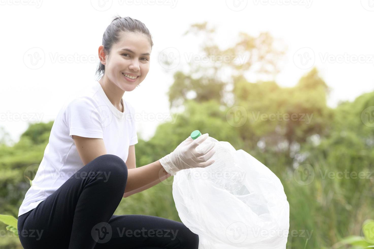 woman is collecting recycling junk on ground , ecological sustainable concept . photo