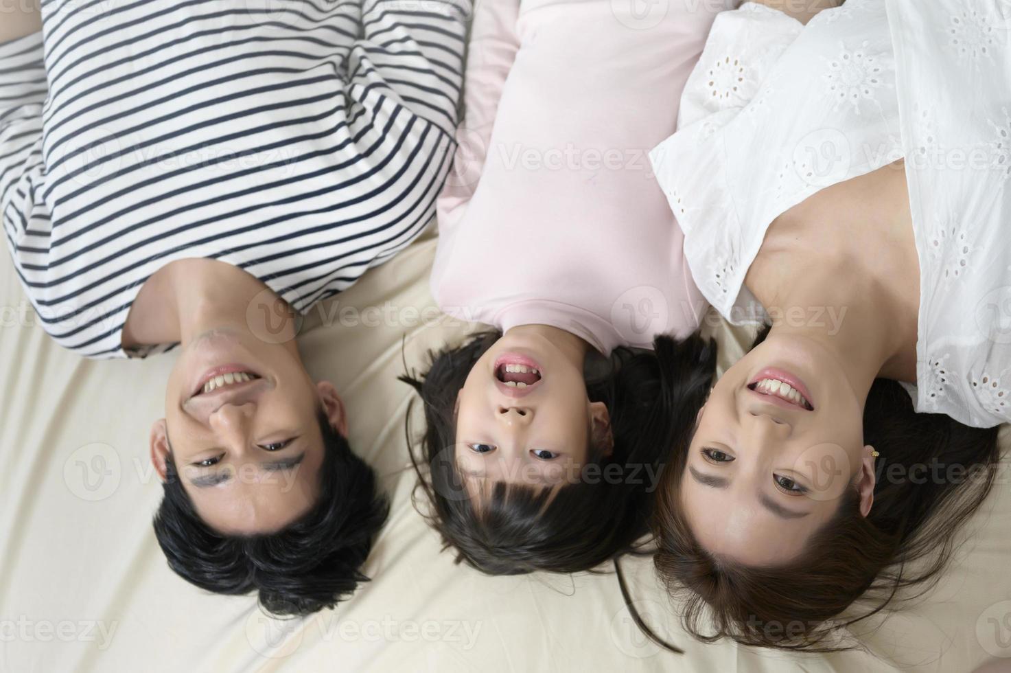 Top view of asian Parents with little daughters on the bed in bedroom, happy family concept photo