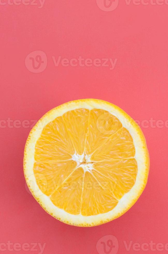 Top view of a one orange fruit slice on bright background in red color. A saturated citrus texture image photo