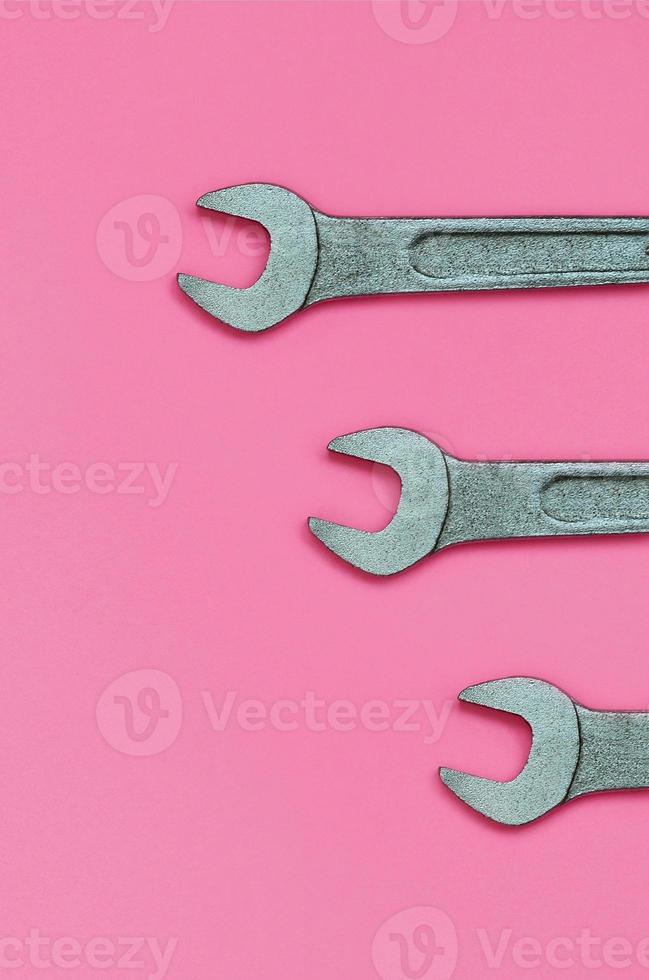 tres llaves metálicas yacen sobre la textura del fondo del papel de color rosa pastel de moda en un concepto mínimo foto