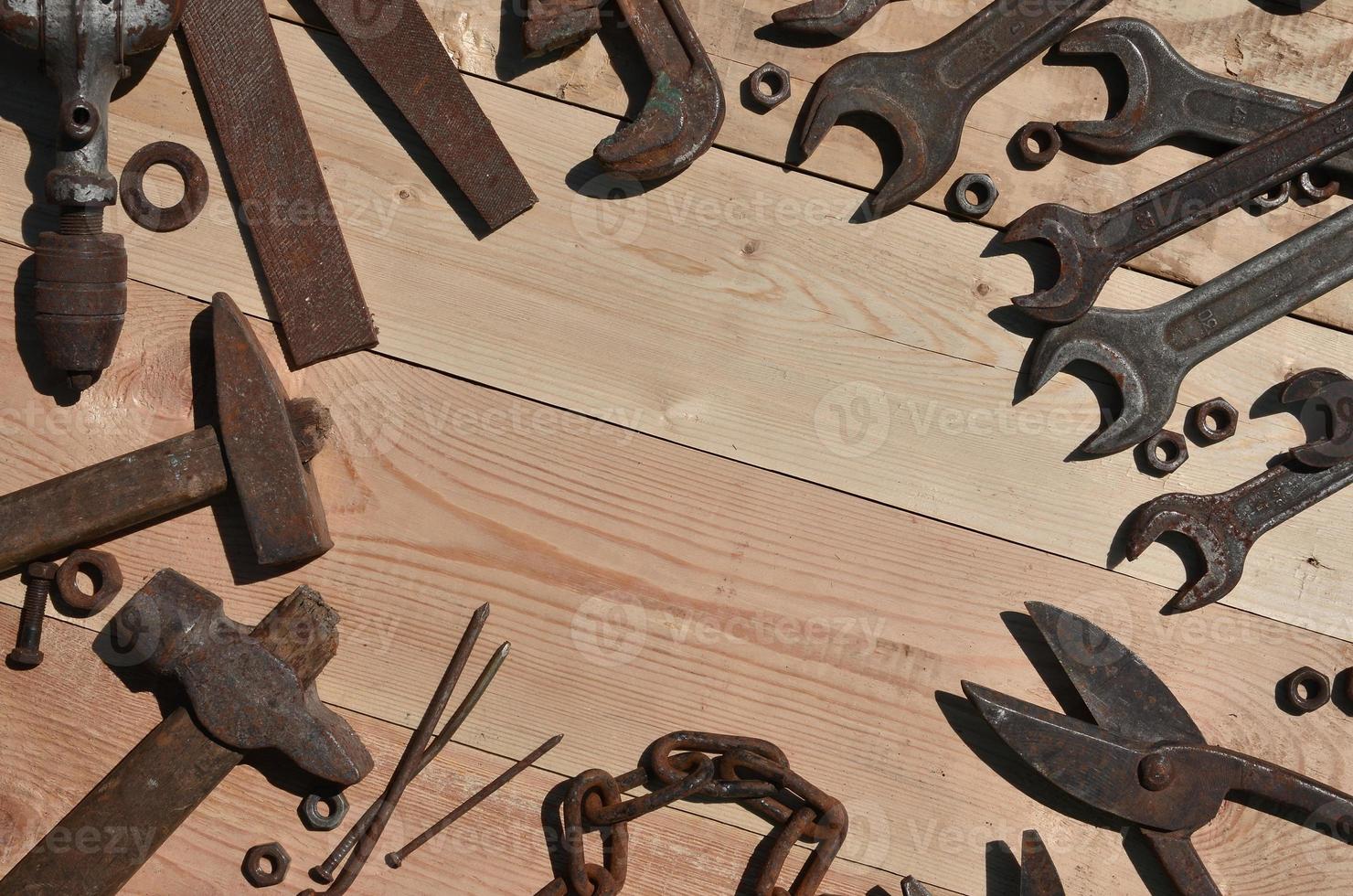 A set of old and rusty tools lies on a wooden table in the workshop photo