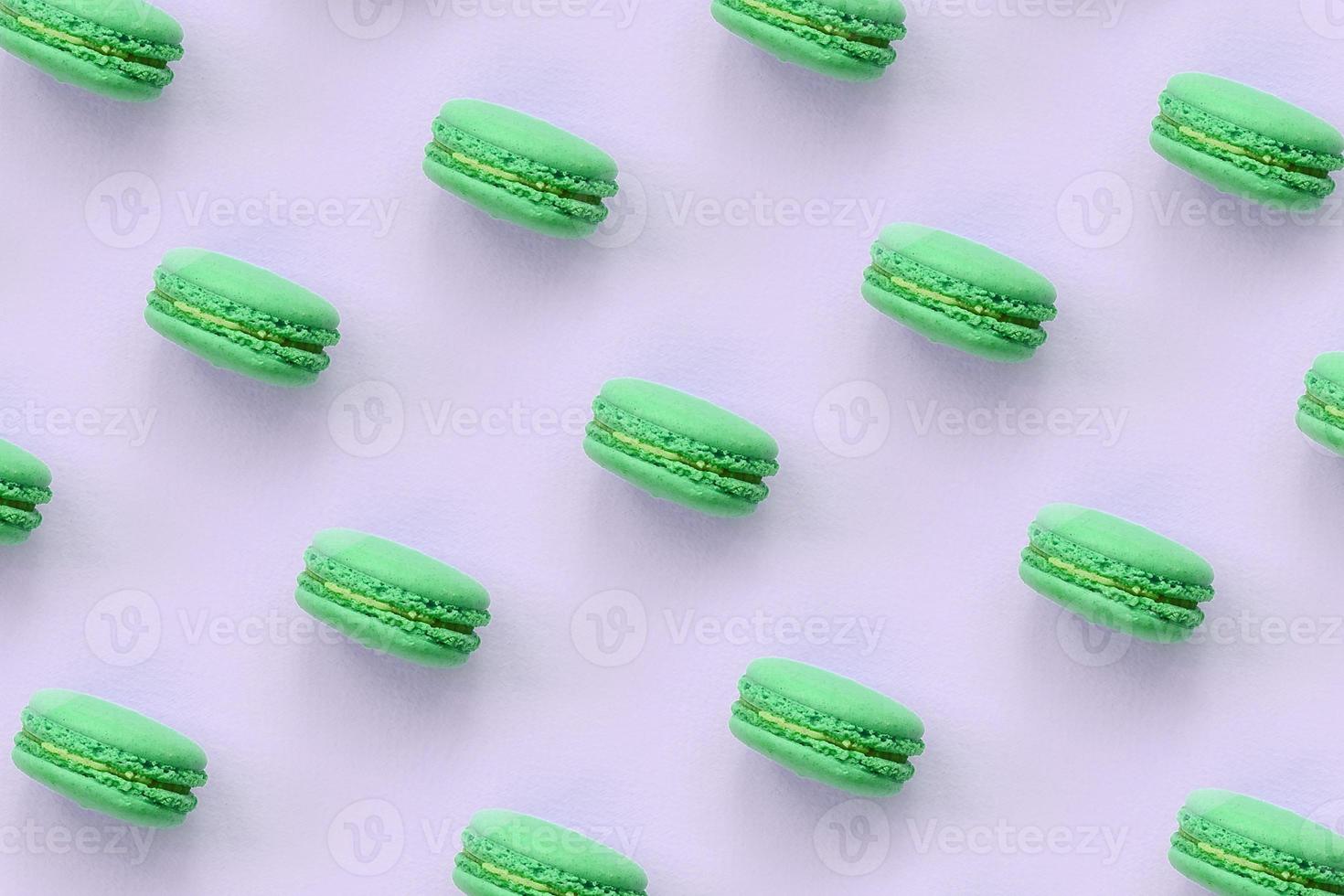 Green dessert cake macaron or macaroon on trendy pastel lilac background top view photo