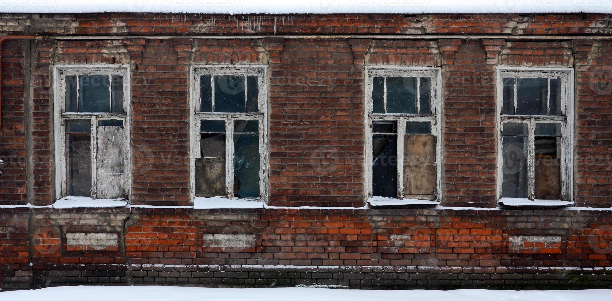 An old brick wall of an apartment house with a lot of boarded up windows without glass photo