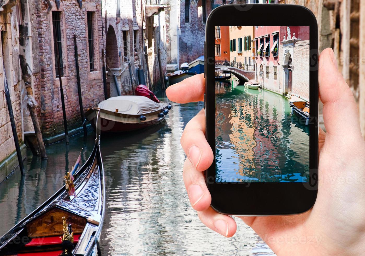 tourist taking photo of canal, gondola, boats