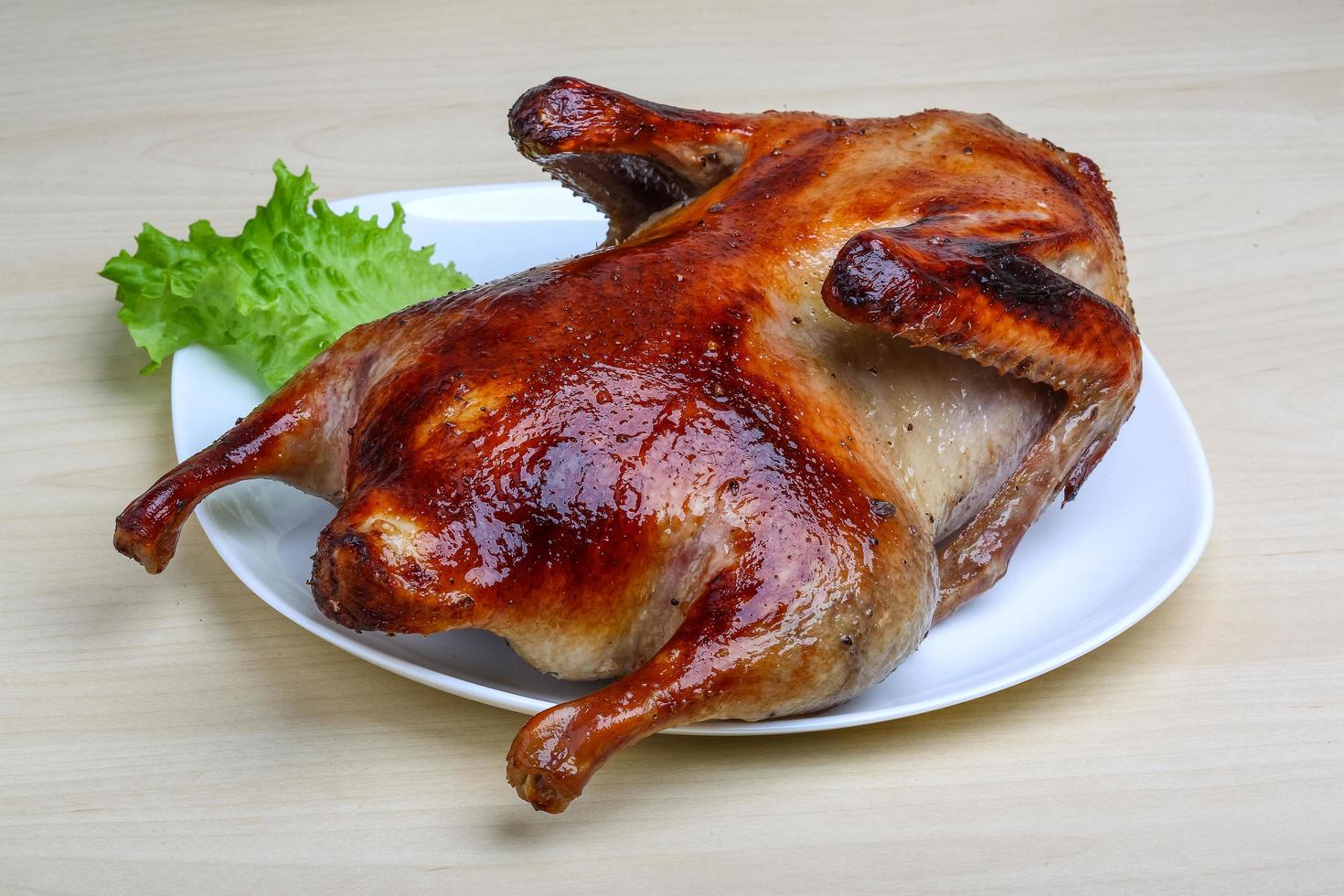 Roasted duck on the plate and wooden background photo