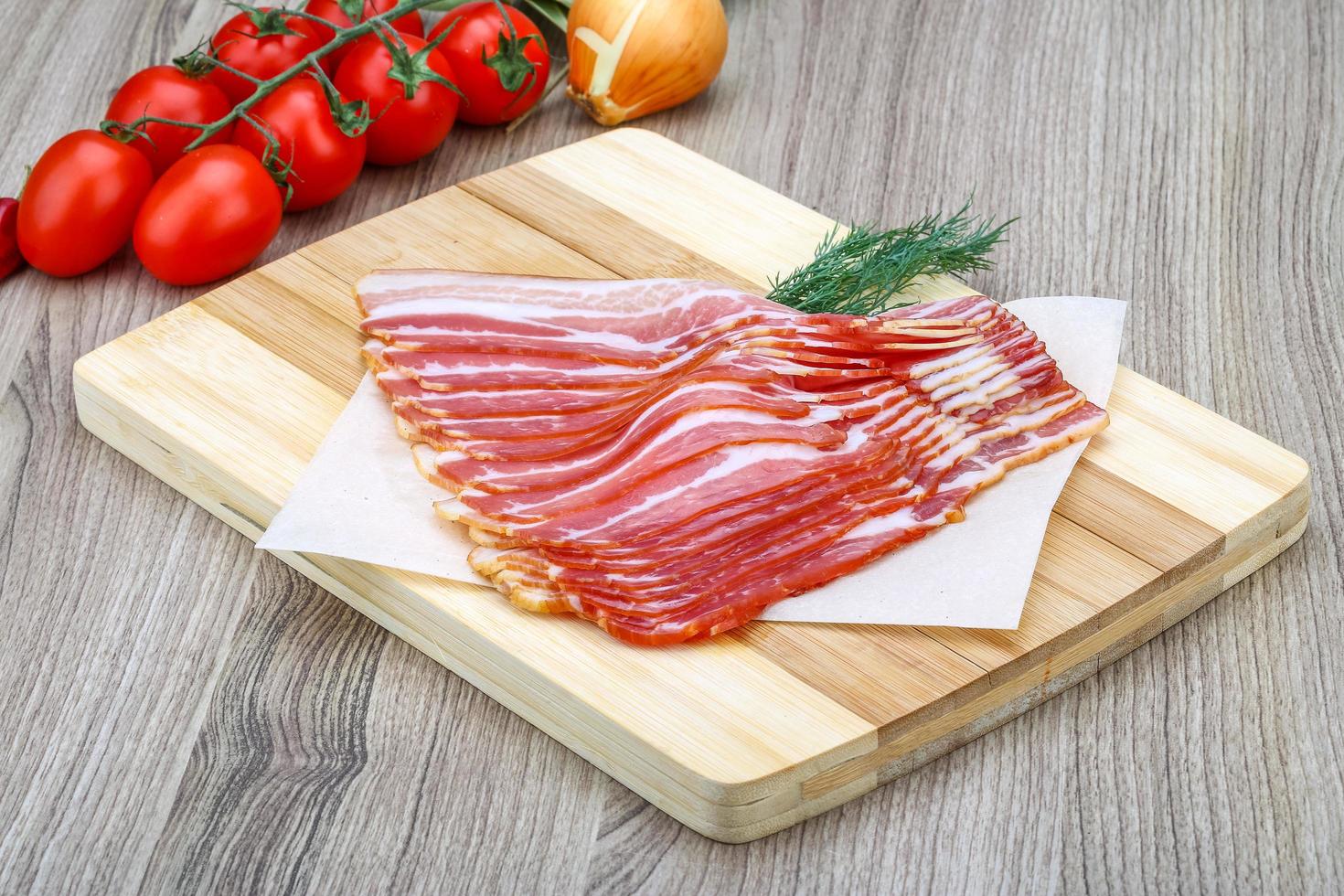 Sliced bacon on wooden board and wooden background photo