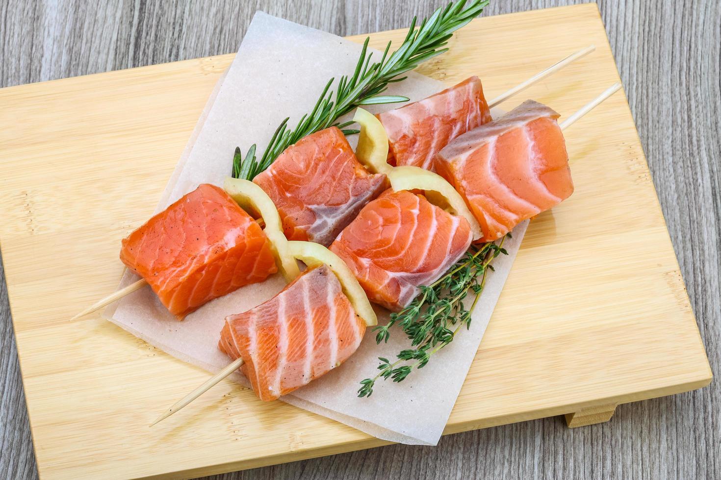 Salmon skewer on wooden board and wooden background photo