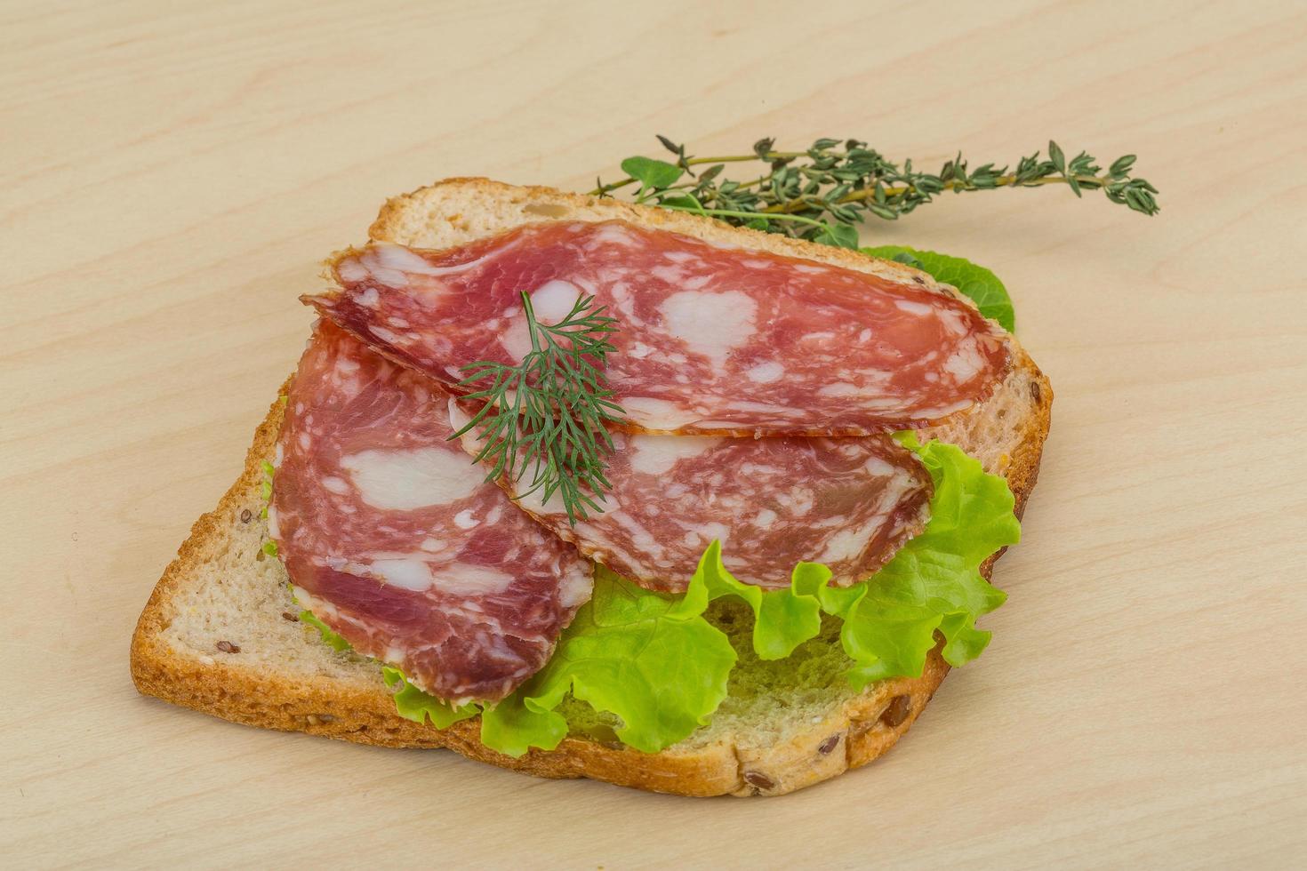 Salami sandwich on wooden background photo