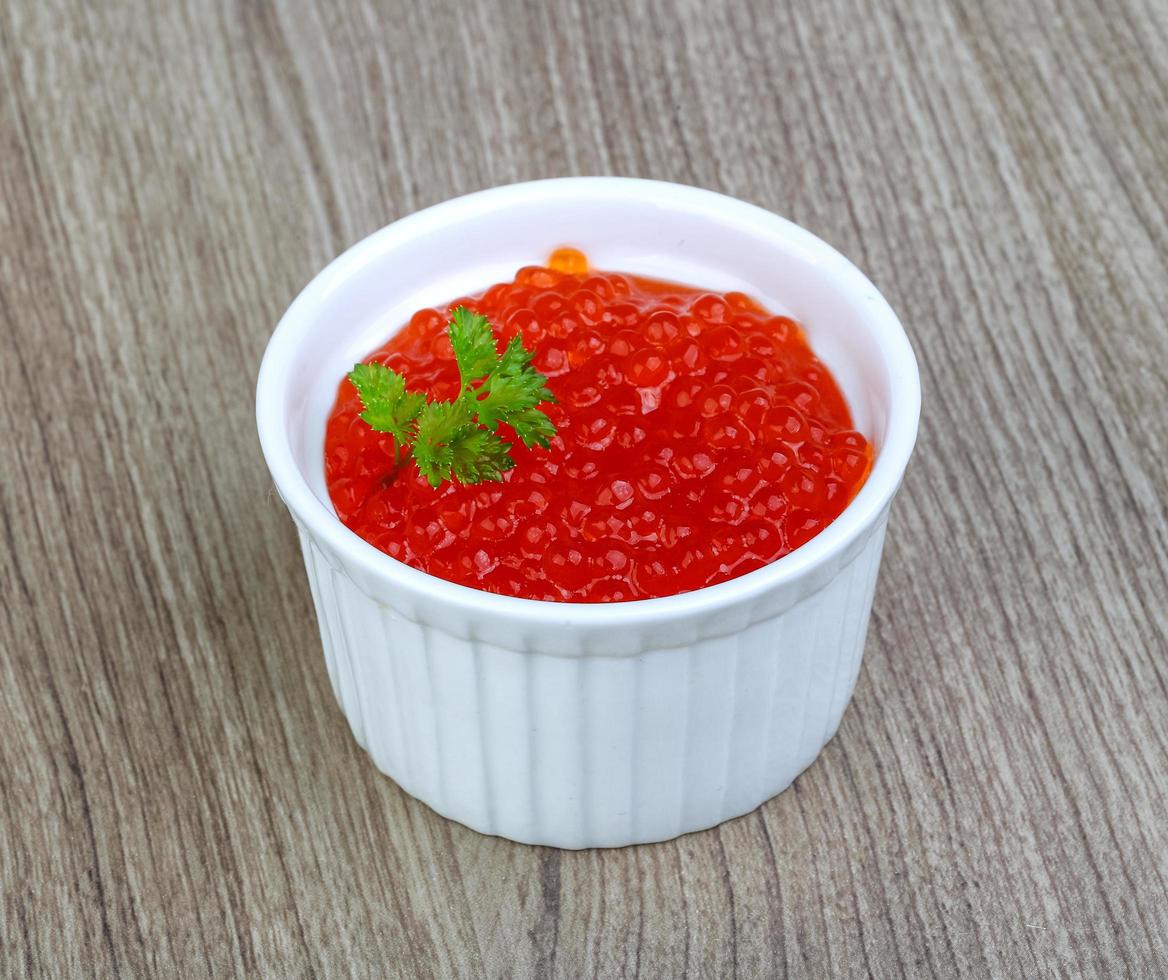 Red caviar in a bowl on wooden background photo