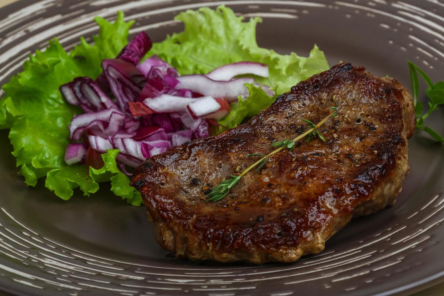 bistec en el plato y fondo de madera foto