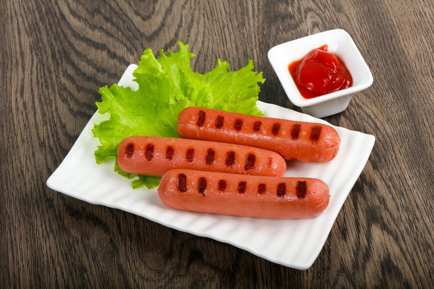 Grilled sausages on the plate and wooden background photo