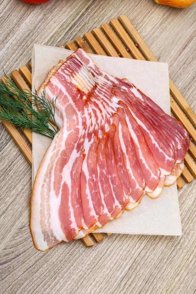 Sliced bacon on wood photo