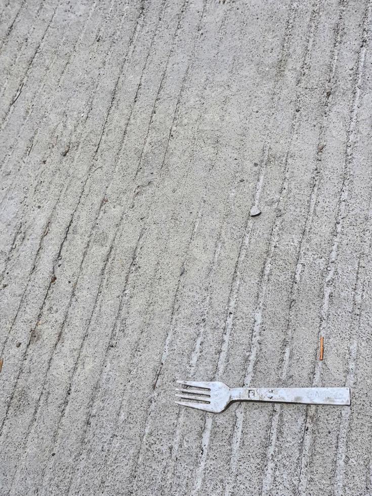 A plastic fork litter on top of a concrete road. Ab photo