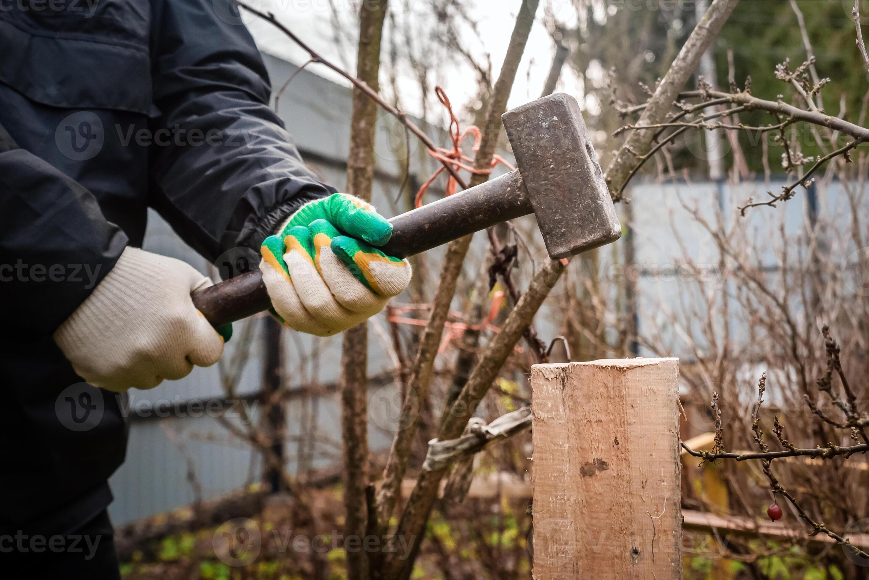 photo of the hands of a man hammering a board with a sledgehammer into