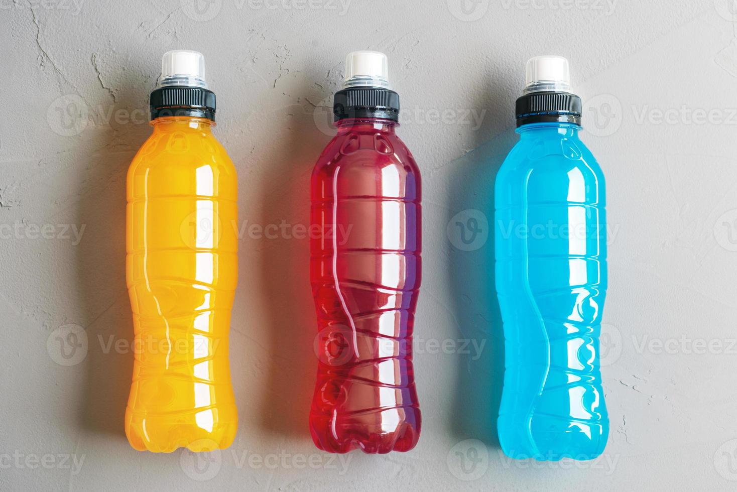 Flat lay shot of three bottles of isotonic drink on a grey concrete background photo