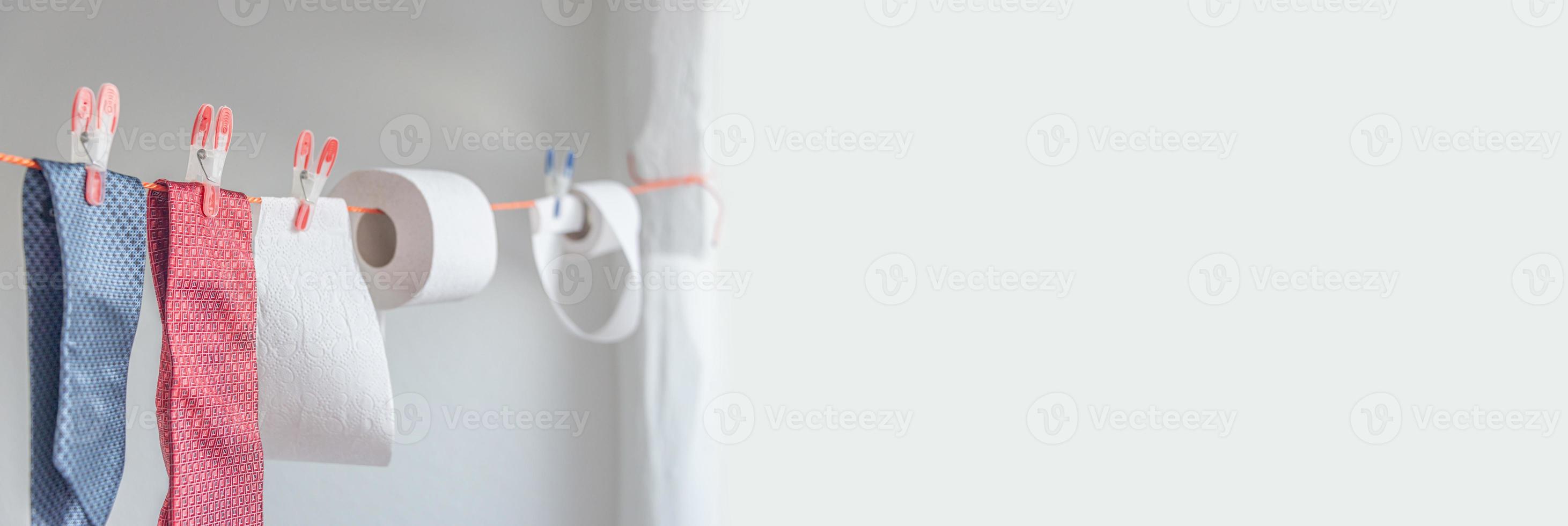 Banner with toilet paper rolls hanging on clothesline for drying and reuse and washing together with expensive ties. Concept of economical, financial crisis. Humorous anecdotic concept with copy space photo
