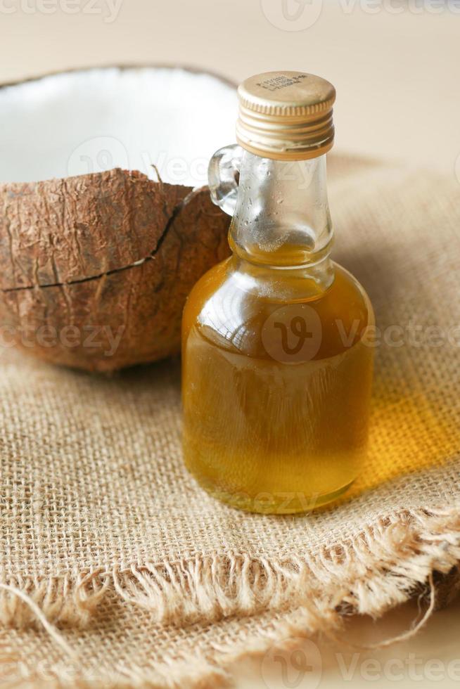 Rebanada de coco fresco y una botella de aceite sobre una mesa foto