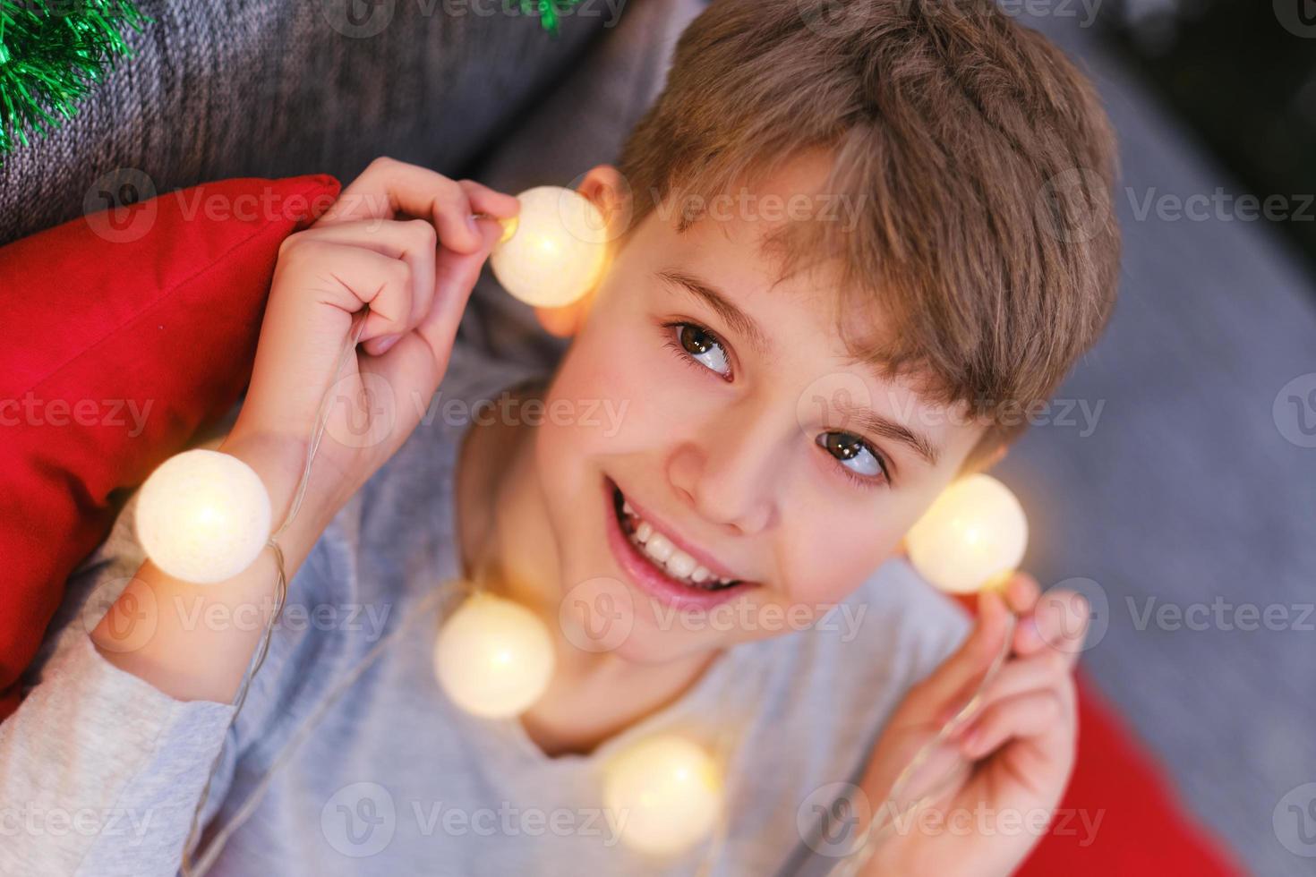 Close-up portrait of a Christmas child with Christmas lights in his hands photo
