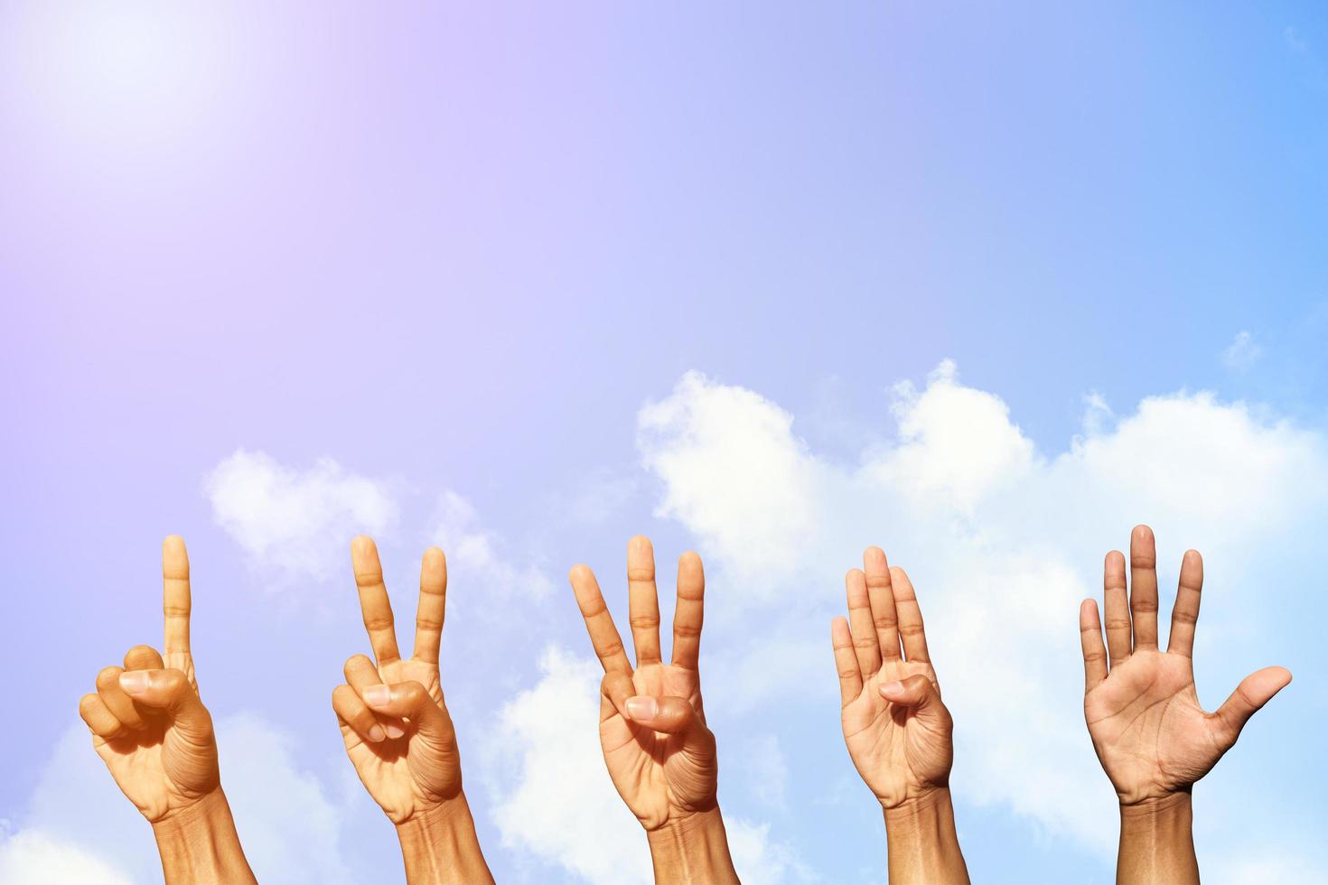 Set of hands counting from one to five behind of fresh air with blue sky and clouds background with copy space for wallpaper or banner photo