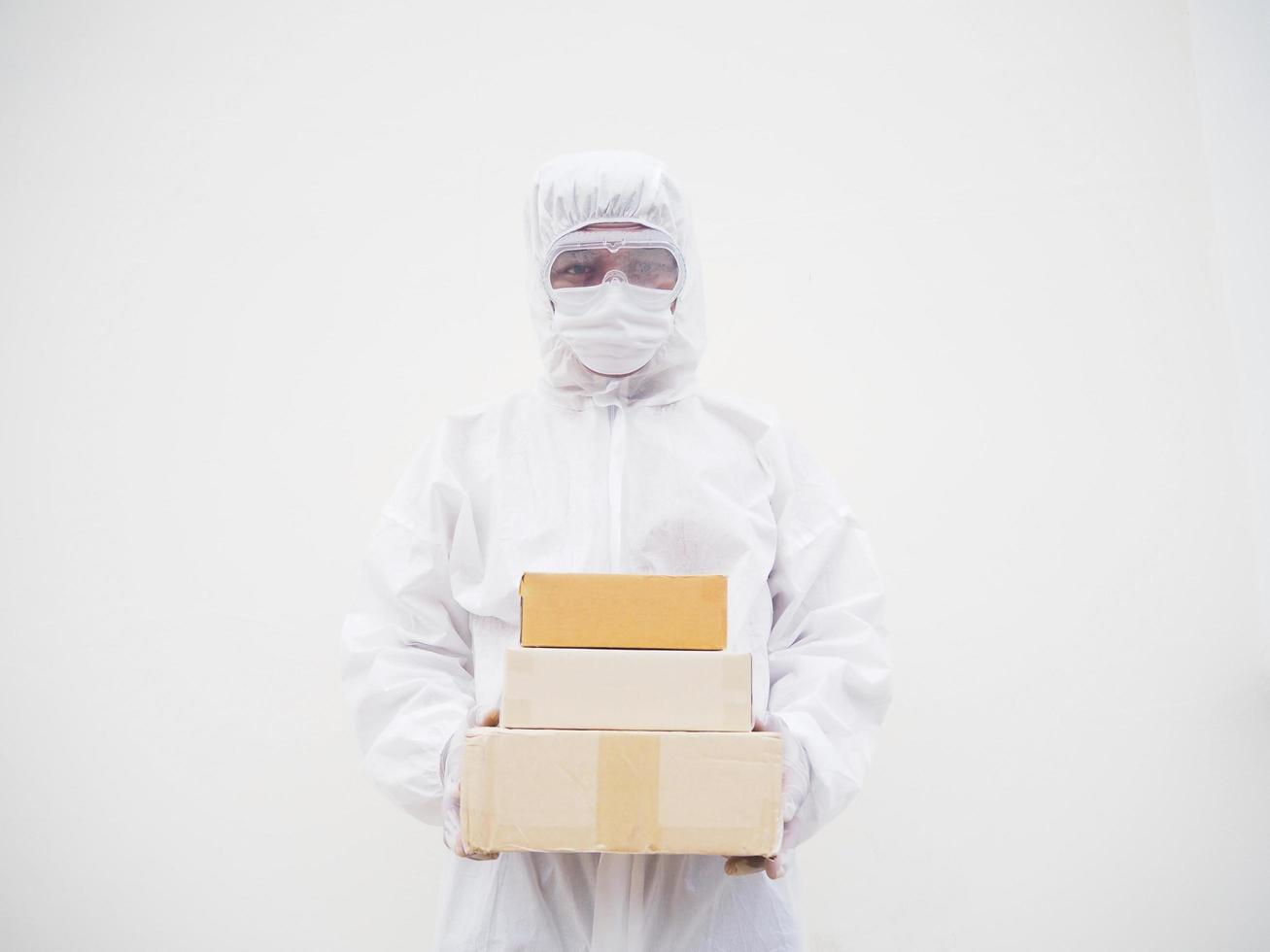 joven con uniforme de suite de ppe mientras sostiene cajas de cartón con guantes médicos de goma y máscara. concepto de coronavirus o covid-19 fondo blanco aislado foto