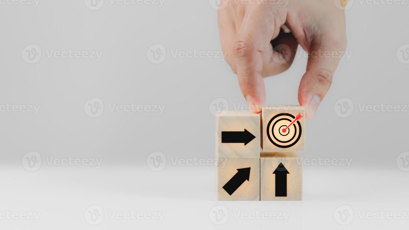 Businessman holds wooden cubes with goal success icon and arrow icon on white background. Business concept growth success process, copy space. photo