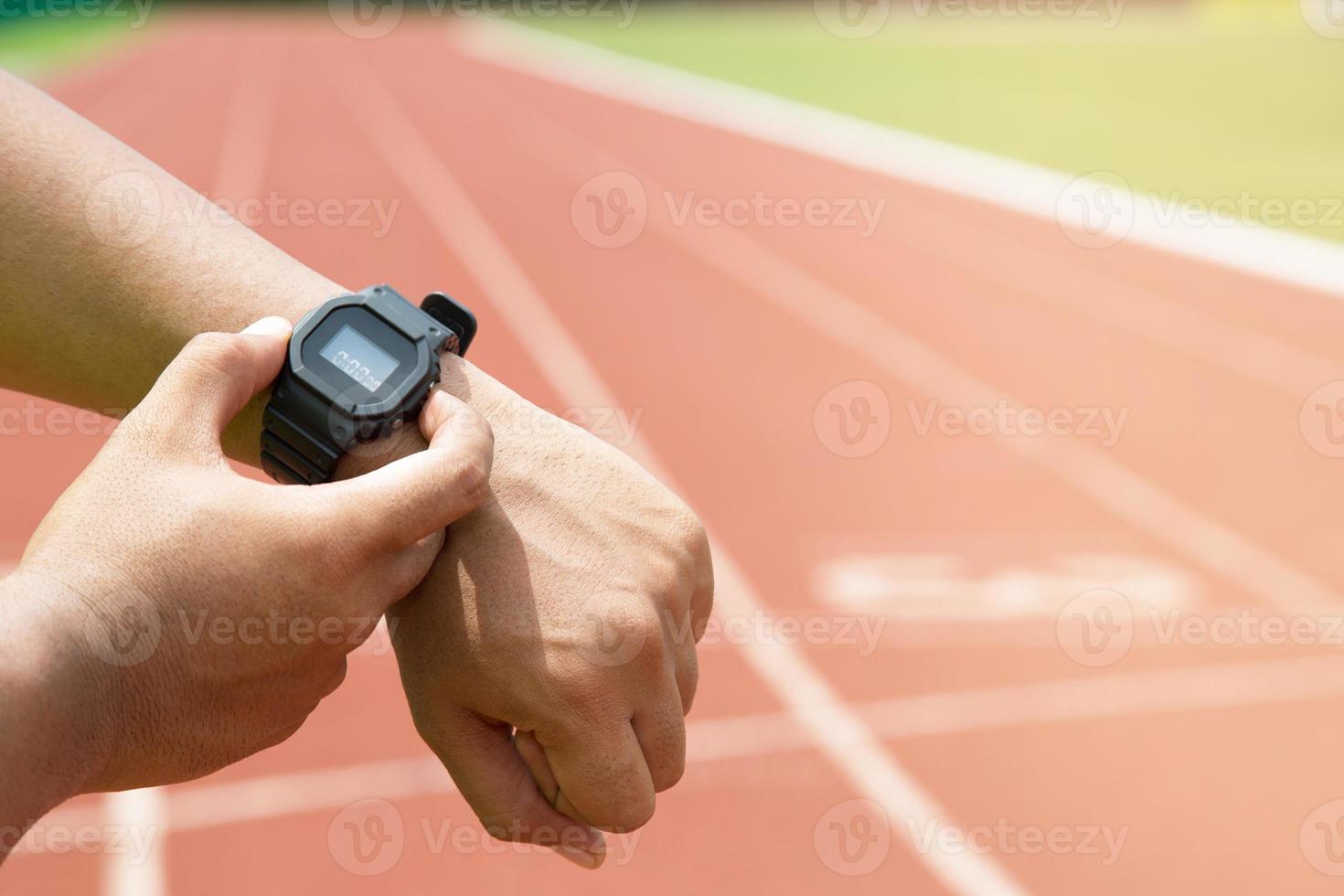 close up hands Athlete checking his watch Race timer runner ready to run on running track. photo