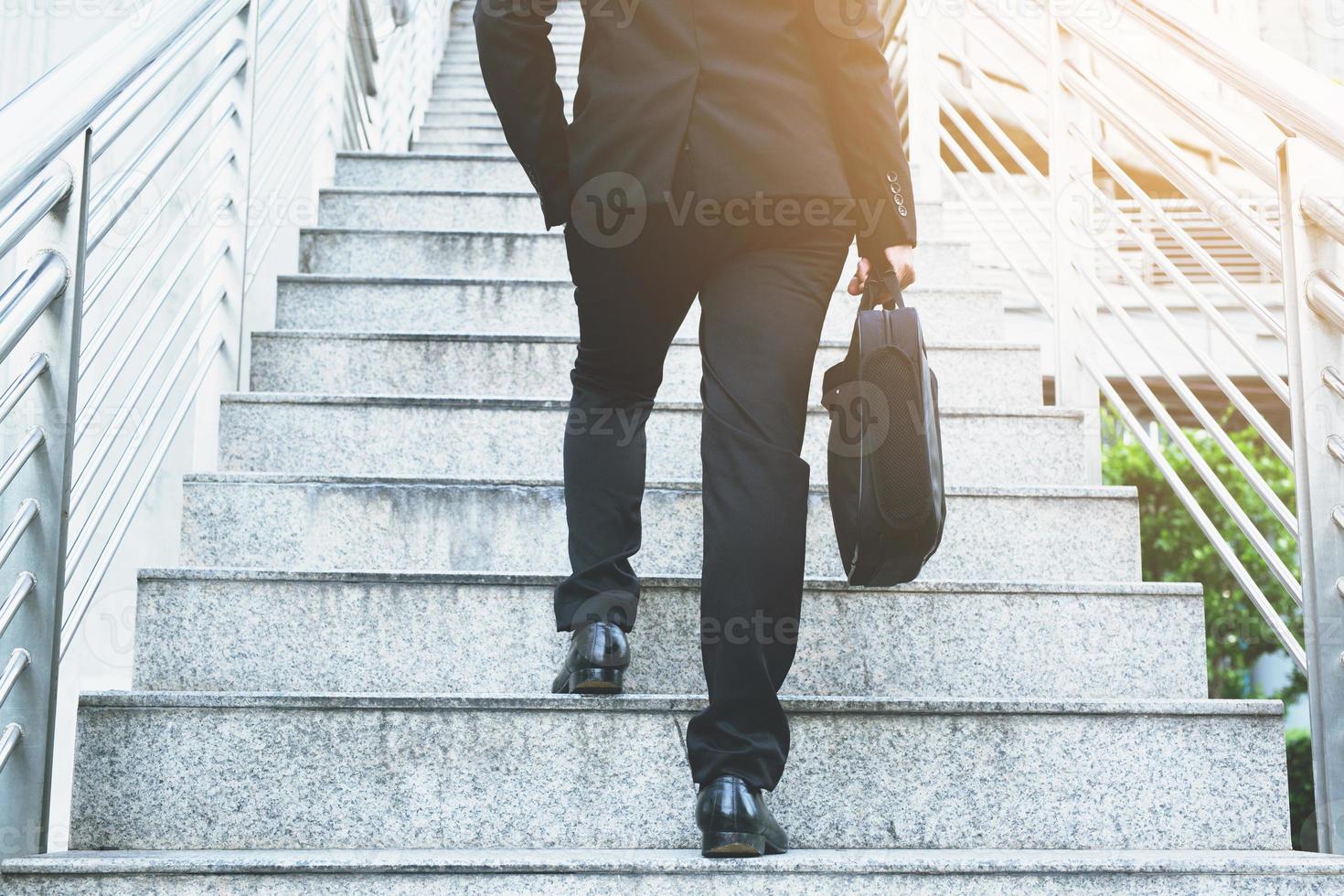 modern businessman hand holding briefcase beside working close up legs walking up the stairs in modern city. in rush hour to work in office a hurry. During the first morning of work. stairway photo