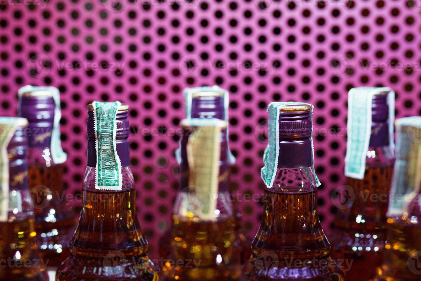 close up Alcoholic beverages in bottles at a on the shelves. Steel grating purple background. photo