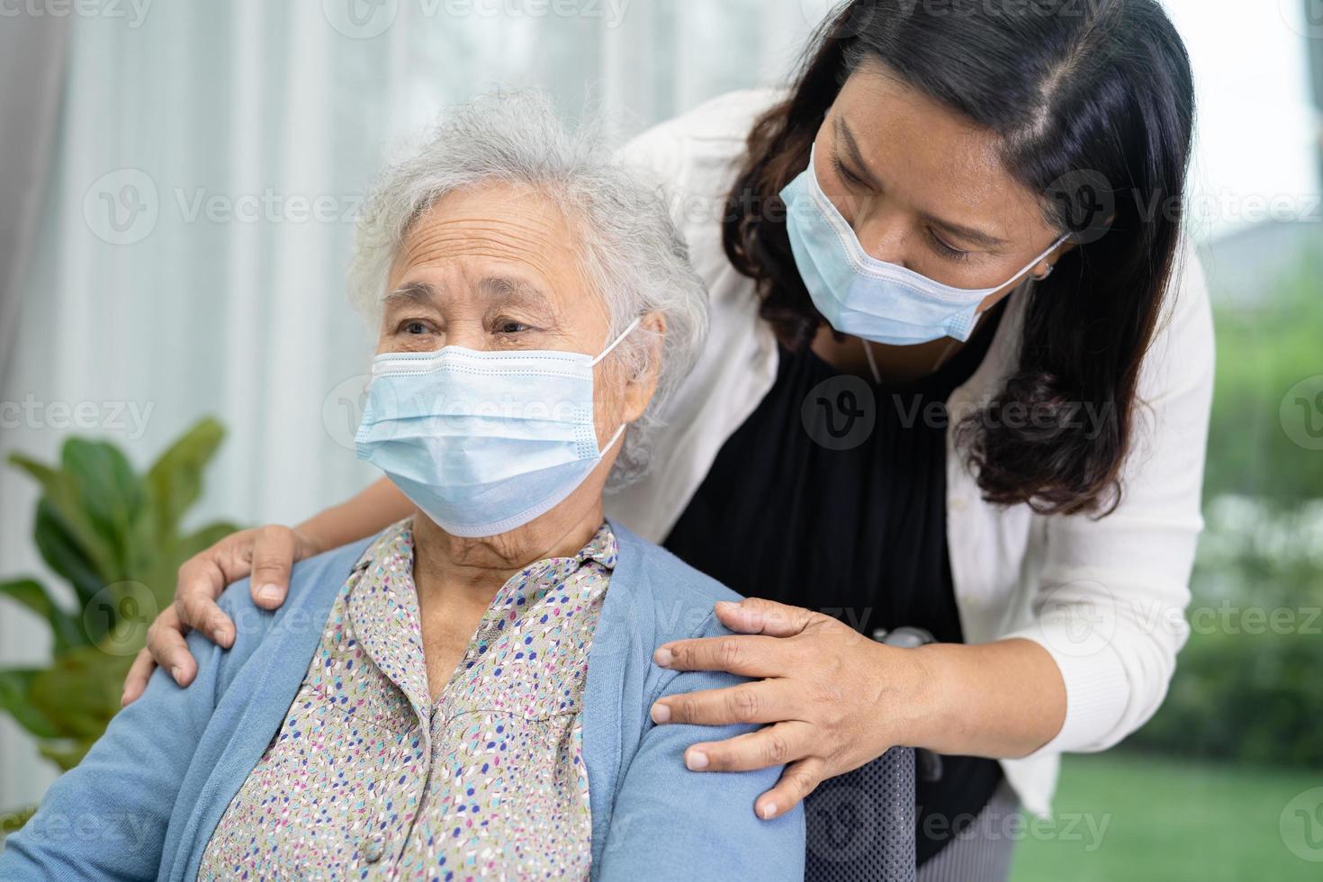 ayudar a una anciana o anciana asiática sentada en silla de ruedas y usando una máscara facial foto