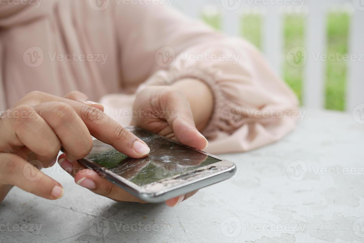 mujeres señalando con el dedo en la pantalla rota del teléfono inteligente foto