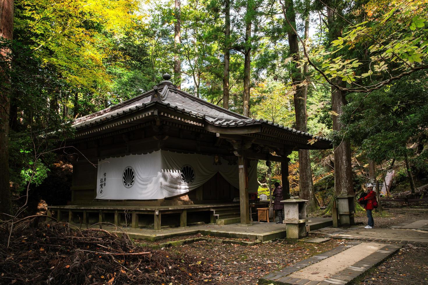 Kurama, Kyoto Prefecture, Kansai, Japan - November 21, 2019 - Tourists pray to the Sojogadanifudodo, a shrine in Kurama-dera, on walking trail between Kurama-dera to Kifune Shrine in Mount Kurama photo
