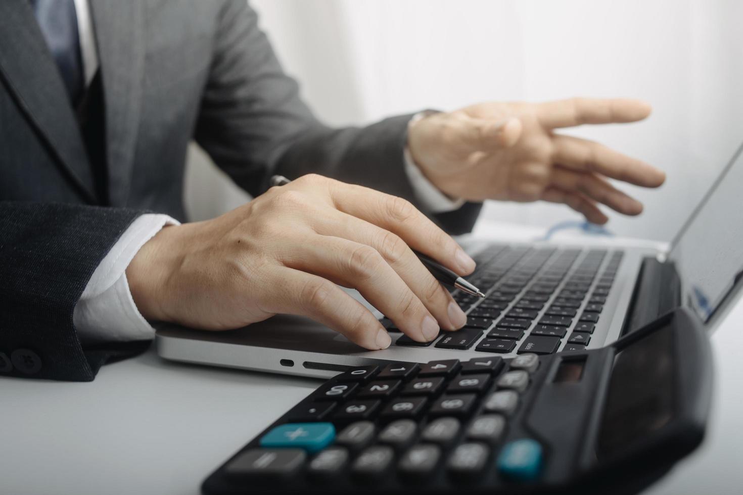 Woman entrepreneur using a calculator with a pen in her hand, calculating financial expense at home office photo