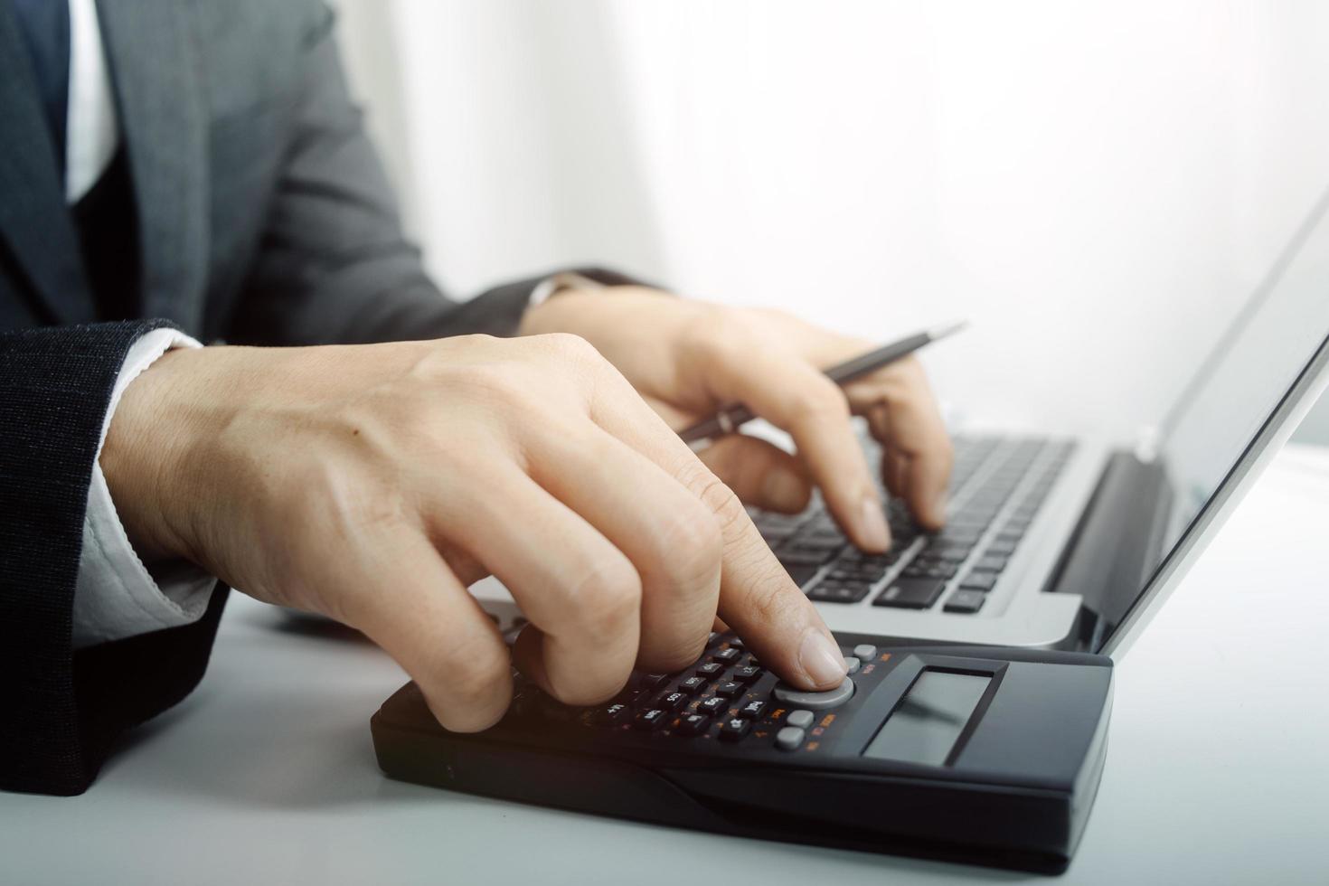 Woman entrepreneur using a calculator with a pen in her hand, calculating financial expense at home office photo