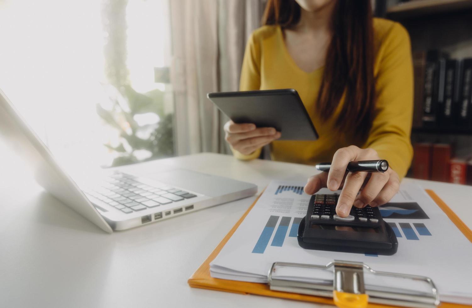 Woman entrepreneur using a calculator with a pen in her hand, calculating financial expense at home office photo