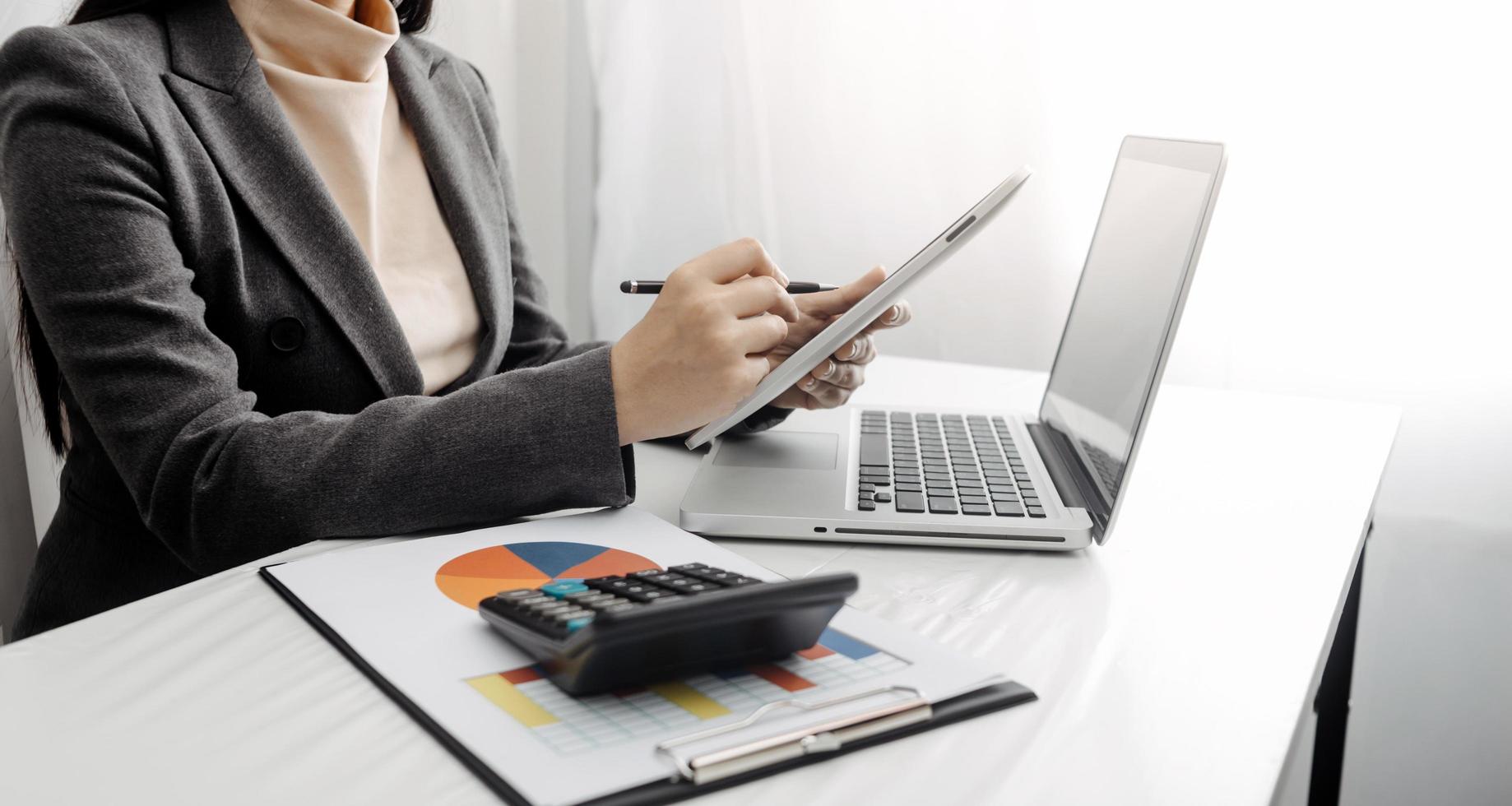 Woman entrepreneur using a calculator with a pen in her hand, calculating financial expense at home office photo