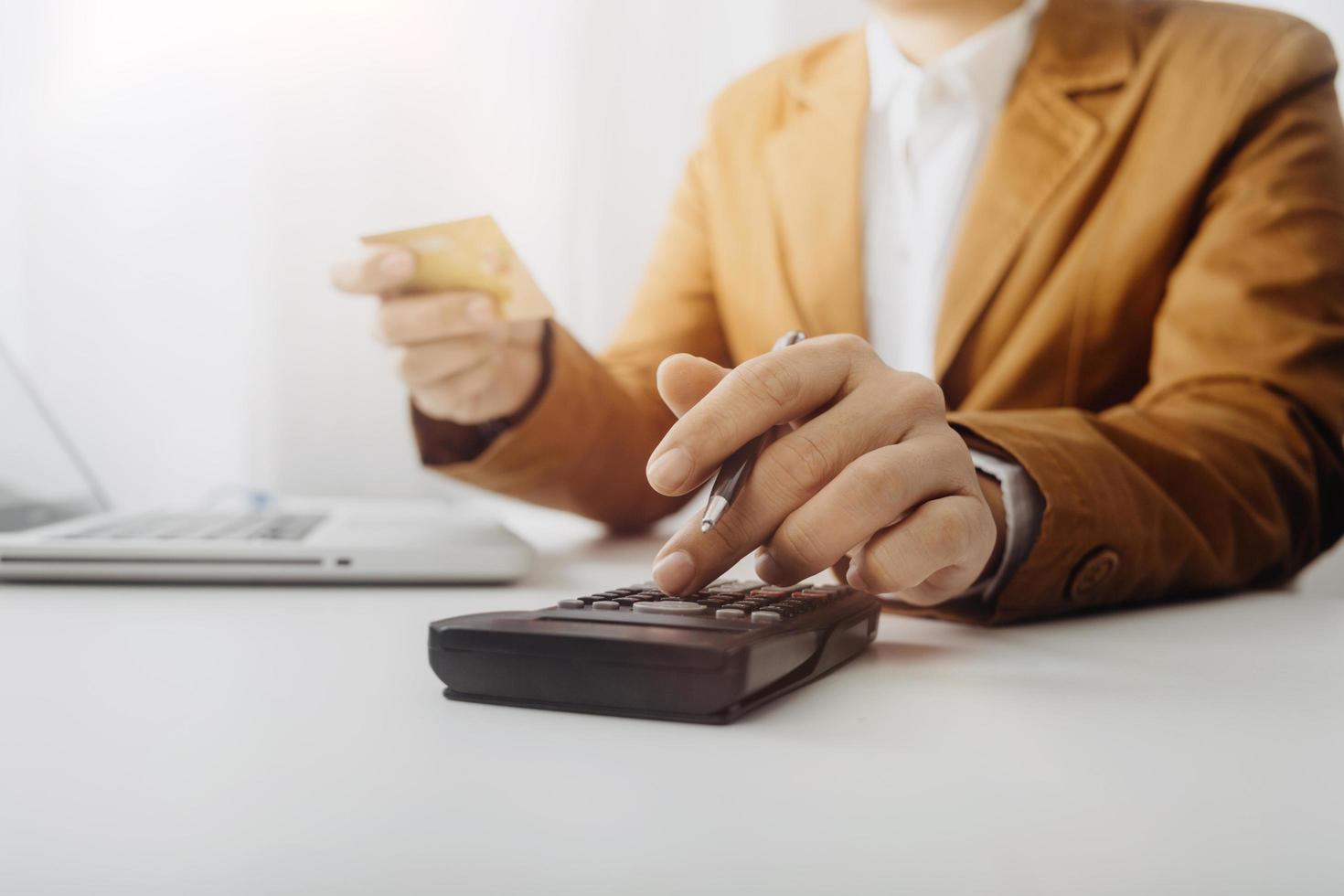 mujer empresaria usando una calculadora con un bolígrafo en la mano, calculando los gastos financieros en la oficina del hogar foto