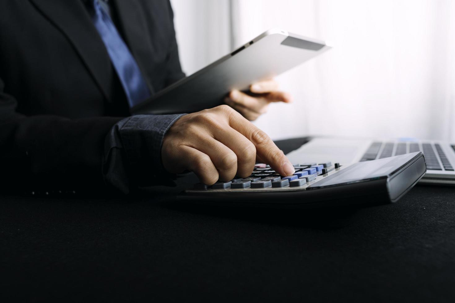 Woman entrepreneur using a calculator with a pen in her hand, calculating financial expense at home office photo