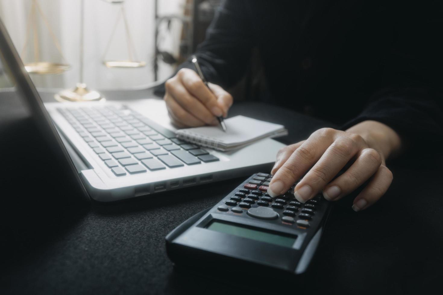 Woman entrepreneur using a calculator with a pen in her hand, calculating financial expense at home office photo