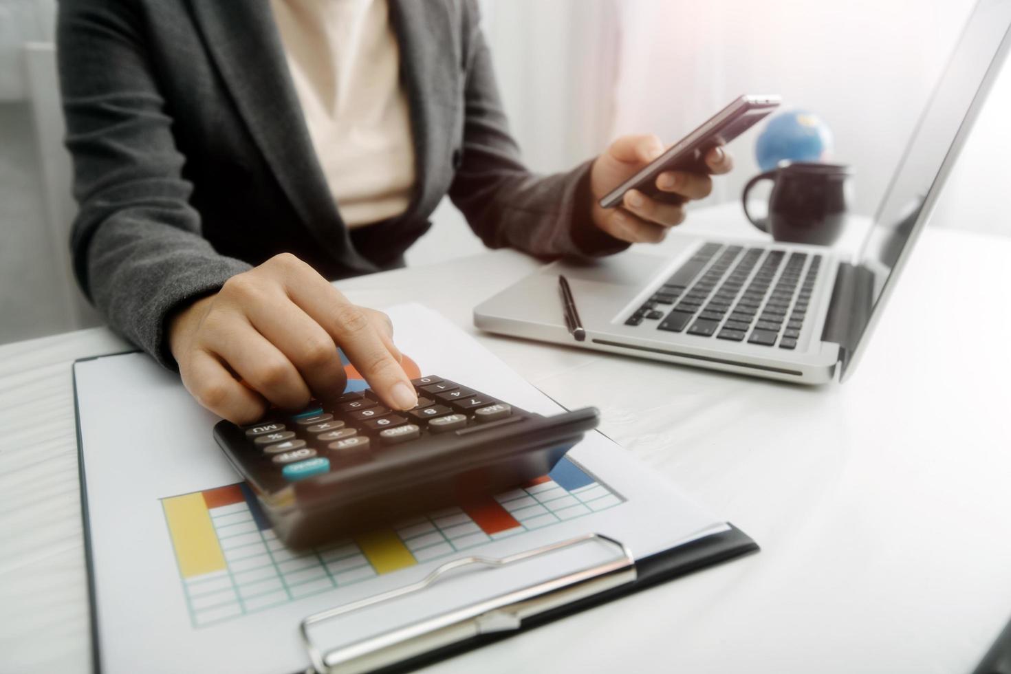 mujer empresaria usando una calculadora con un bolígrafo en la mano, calculando los gastos financieros en la oficina del hogar foto