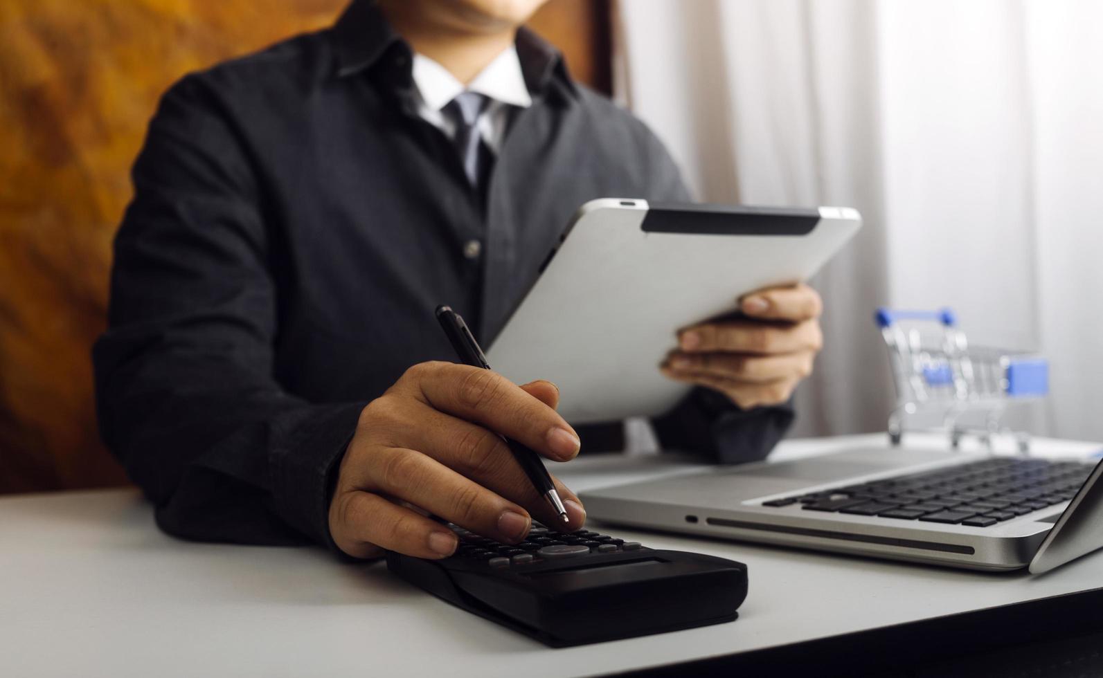 Woman entrepreneur using a calculator with a pen in her hand, calculating financial expense at home office photo