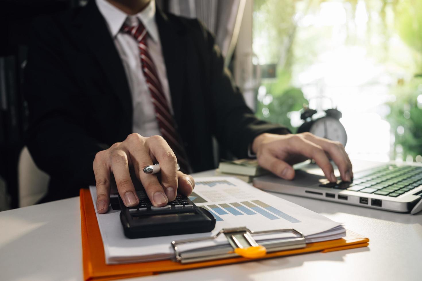 Woman entrepreneur using a calculator with a pen in her hand, calculating financial expense at home office photo